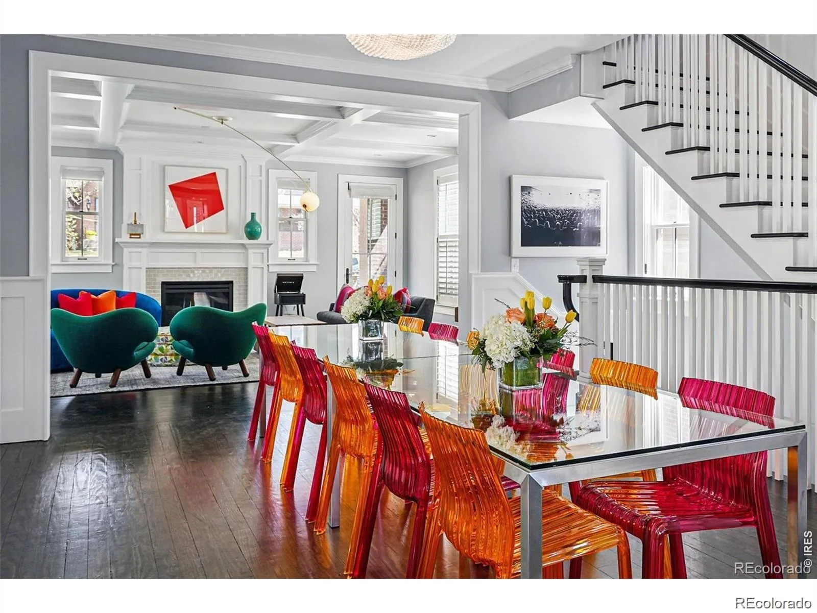 Dining room with glass table and colorful acrylic chairs opening to a living room, 201 South Lafayette Street, Denver