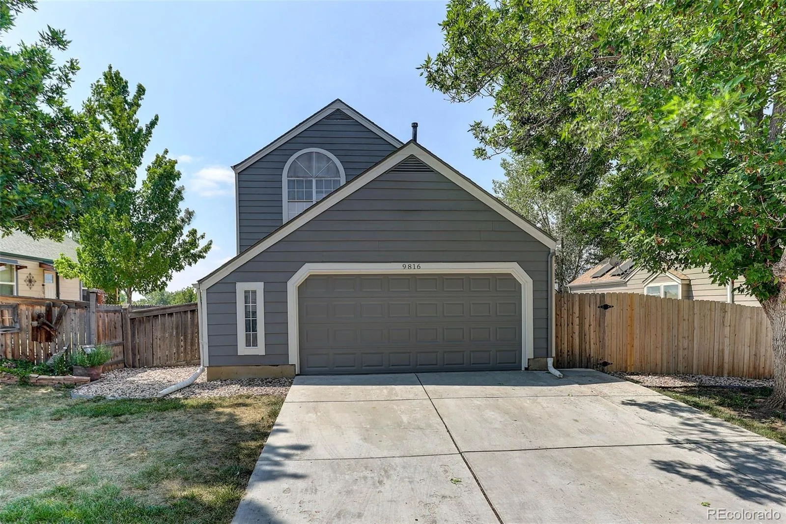 Two-story home with grey siding and arched window above a two-car garage, 9816 West Friend Place, Littleton