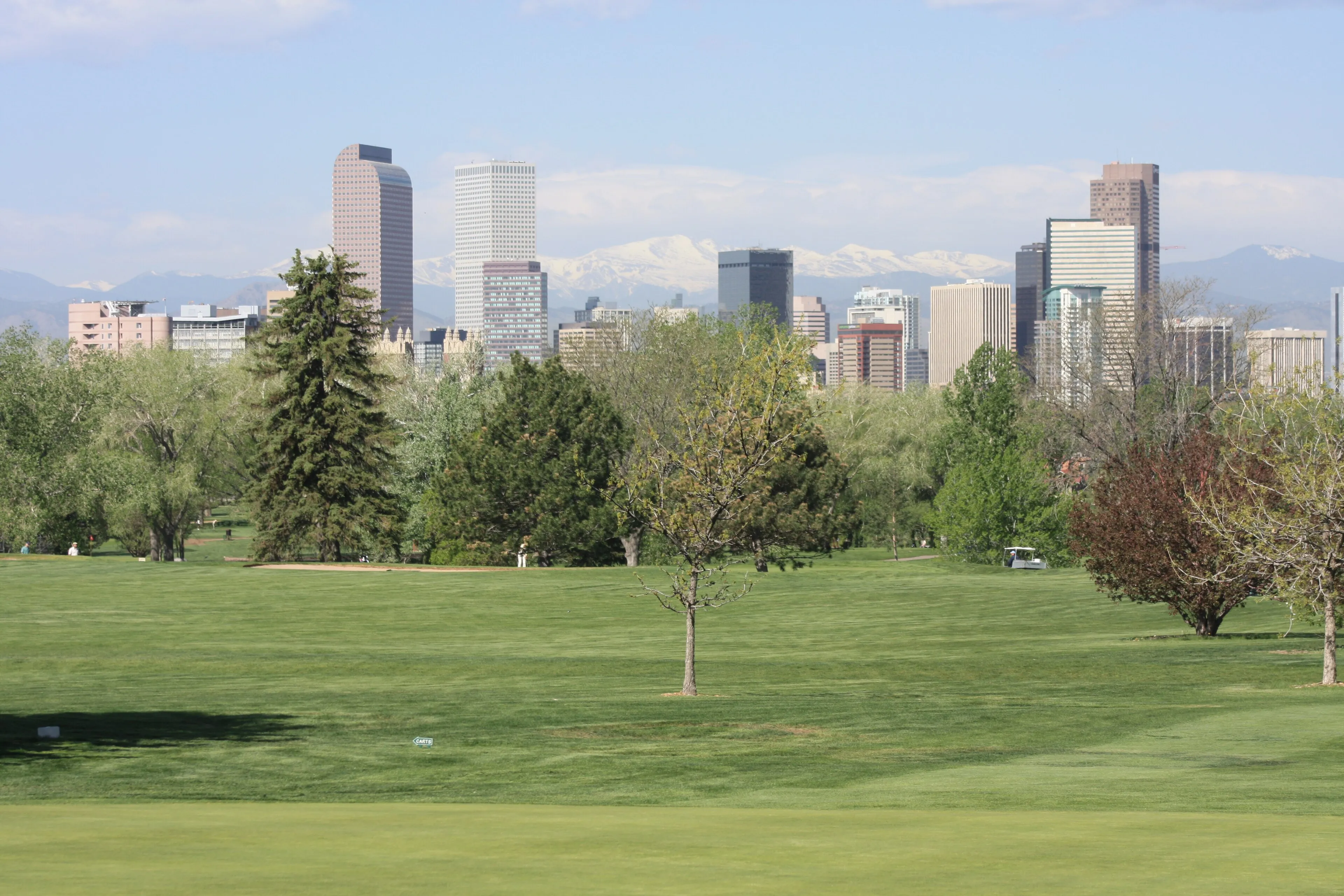 Denver skyline with snow-capped Mount Blue Sky in the distance, seen across City Park
