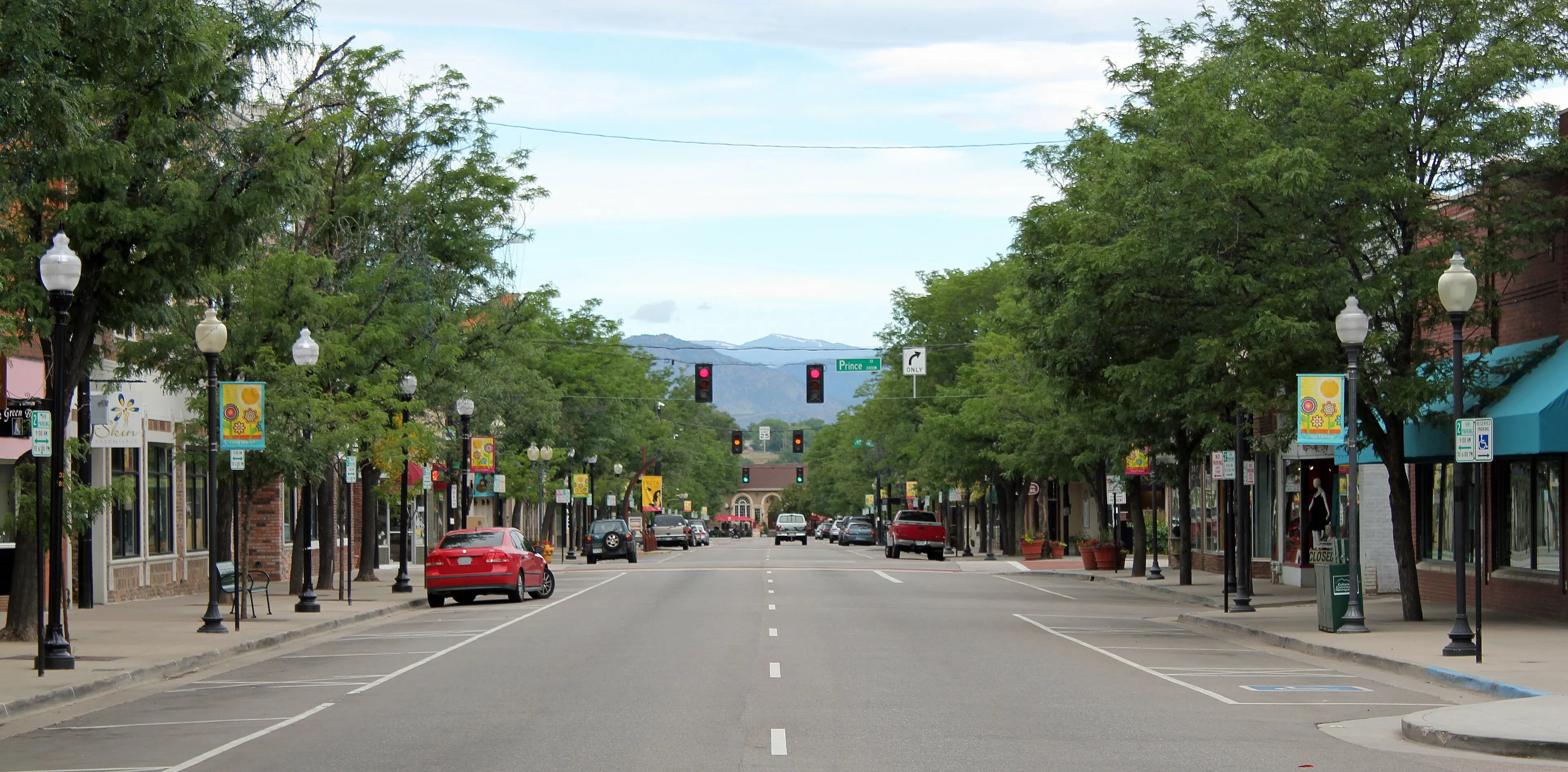 Main Street in downtown Littleton looking west toward the mountains, lined with trees and historic storefronts